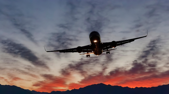 It is best to fly coach to nearby destinations, and avoid non-essential flights. An airliner at sunset | Photo: Sergei25, Shutterstock