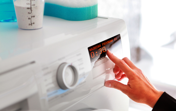 Short washing programs in cold water also save on electricity. A woman setting the washing machine program | Photo: ssuaphotos, Shutterstock